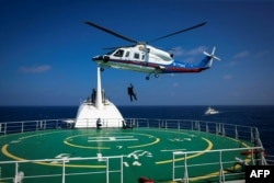 FILE - Helicopter rescue crew members practice rescue techniques during an emergency drill held by Sansha city's maritime search and rescue center in the South China Sea near Sansha, in south China's Hainan province, July 14, 2016.