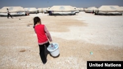 A Syrian girl carries a bucket filled with bottles of precious water to her family's tent in Jordan's al Za'atri refugee camp, September 04, 2012. (UNHCR)