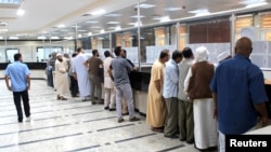 FILE - Libyan people gather in front of a counter in a bank to buy foreign currency in Misrata, Oct. 28, 2018. 