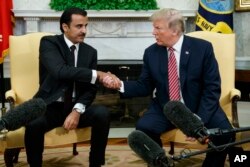 FILE - President Donald Trump shakes hands with the emir of Qatar, Sheikh Tamim al-Thani, in the Oval Office of the White House, April 10, 2018, in Washington.
