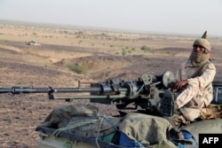 FILE - A Tuareg fighter of the Coordination of Movements of the Azawad (CMA) stand on a pick up truck with a machine gun near Kidal, northern Mali, Sept. 28, 2016,