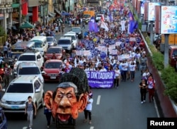 An effigy of Philippine President Rodrigo Duterte is seen while women's rights activists march along a busy street during a celebration of the International Women's Day in Quiapo city, Metro Manila, Philippines, March 8, 2018.