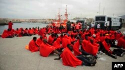Des migrants sauvés au large de la côte espagnole, sont assis à même le sol au port de Tarifa, 11 Août, 2014.