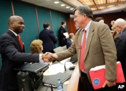 Georgia state Rep. Rick Jasperse, R-Jasper, right, shakes hands with Assistant Legislative Counsel Julius Tolbert in Atlanta after a Senate committee approved Jasperse's bill that would permit those with concealed carry weapons licenses to bring their guns onto public college campuses, March 7, 2016. Georgia's governor later vetoed the bill.