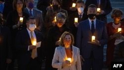 La presidenta de la Cámara de Representantes de Estados Unidos, Nancy Pelosi (C), entre otros miembros del Congreso sostienen velas eléctricas mientras participan en una vigilia en memoria de las 800.000 personas que han muerto de Covid-19 en los Estados Unidos, en Washington, DC el 14 de diciembre de 2021.