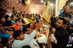 FILE - Pakistani television show host Aamir Liaquat Hussain, right, distributes gifts to the audience during an Islamic quiz show in Karachi, July 31, 2013.
