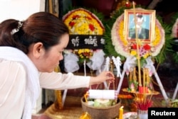 FILE - Sam Chanthy, wife of Chut Wutty, director of the Phnom Penh-based environmental watchdog Natural Resource Protection Group, lights a stick of incense during Wutty's funeral at his house in Kandal province, April 28, 2012.