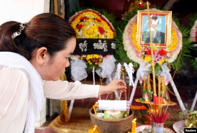 FILE - Sam Chanthy, wife of Chut Wutty, director of the Phnom Penh-based environmental watchdog Natural Resource Protection Group, lights a stick of incense during Wutty's funeral at his house in Kandal province, April 28, 2012.