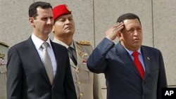 Syrian President Bashar Assad, left, and Venezuelan President Hugo Chavez, right, review the honor guards at the Syrian presidential palace, in Damascus, 21 Oct. 2010
