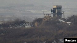 North Korean soldiers watch the South Korean side from a lookout tower at their observation post near the border truce village of Panmunjom in the demilitarized zone (DMZ) separating the two Koreas. South Korea says the sides are removing landmines from the area.