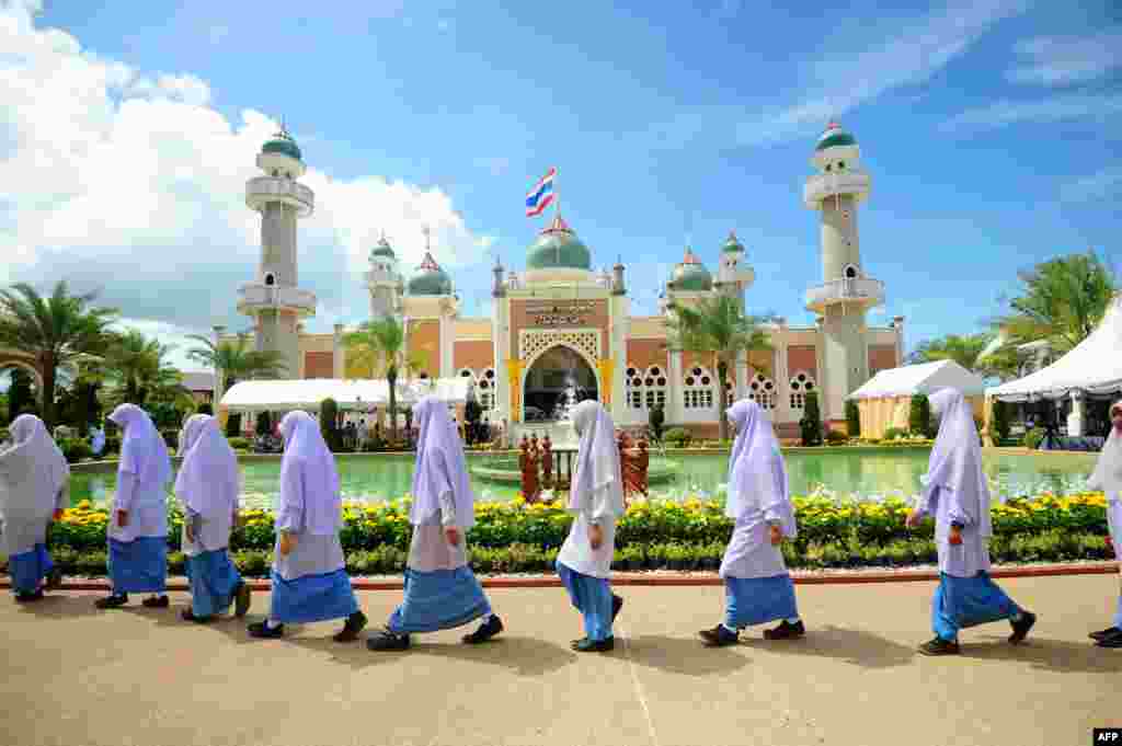 Girls walk past Pattani mosque while waiting for the arrival of Thai Crown Prince Maha Vajiralongkorn during a royal visit to the southern Thai province of Narathiwat.