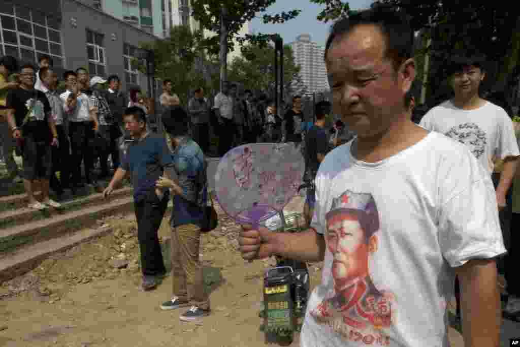 一名挺薄男子身穿印有毛澤東像的體恤衫，手持寫有&ldquo;薄熙來&rdquo;字樣的扇子出現在濟南中級人民法院附近。（2013年8月22日）