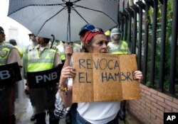 A woman holds a sign with a message that in reads in Spanish; "Revoke hunger" during a protest march in Caracas, Venezuela, July 27, 2016.