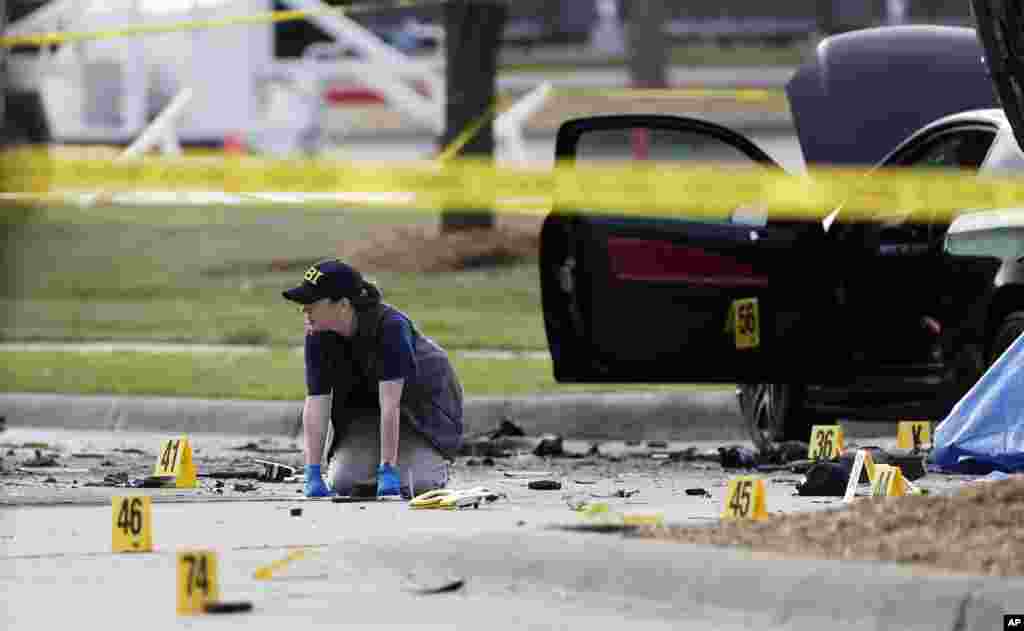 An FBI crime scene investigator examines the site where two gunmen were killed in a shootout with police, near the Curtis Culwell Center in Garland, Texas, May 4, 2015.