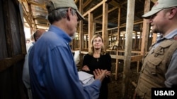 Bill Berger, who leads a USAID disaster assistance response team, briefs administrator Nancy Lindborg at an Ebola treatment unit construction site in Monrovia, Liberia, Oct. 1, 2014.