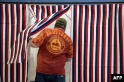 FILE - A man enters a voting booth at a youth center in Manchester, New Hampshire.