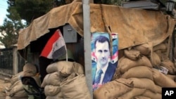 Hunkering down: a poster of Syria's president at a checkpoint on the outskirts of Damascus, January 2012.