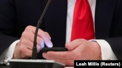Predsednik Donald Tramp dodiruje ekran svog mobilnog telefona (Foto: REUTERS/Leah Millis)