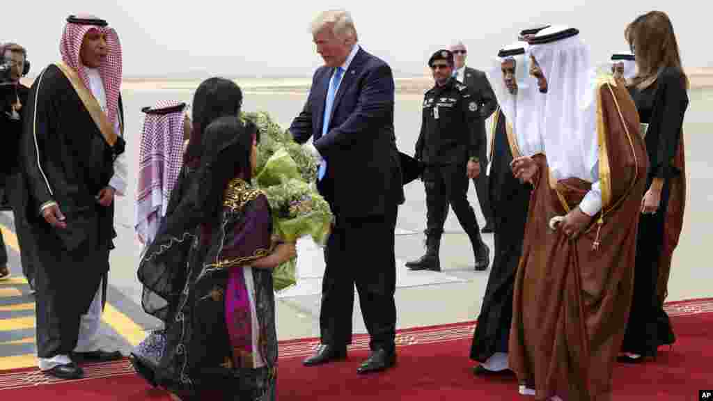 Le président Donald Trump, au centre, reçoit un bouquet de fleurs de bienvenue aux côtés du roi saoudien Salman à l&rsquo;aéroport international roi Khalid, Ryad 20 mai 2017.