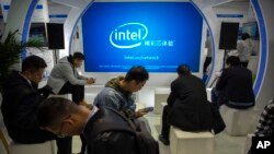 Orang-orang menggunakan smartphone mereka di layar untuk perusahaan teknologi Intel di Expo di Beijing, Kamis, 31 Oktober 2019. (Foto: AP)