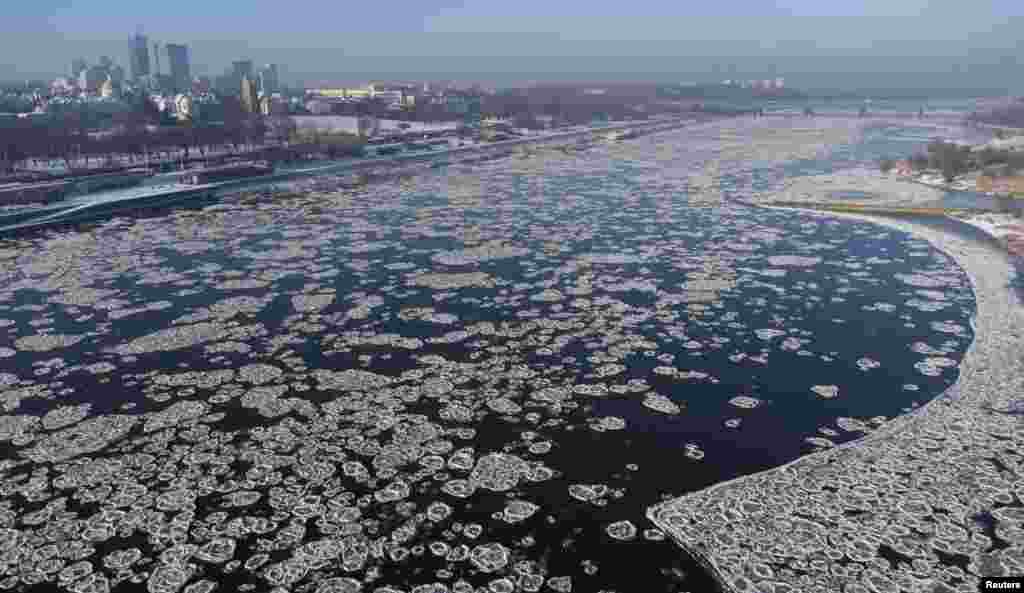 Shuga (Sryz) ice floes in shape of discs on Vistula river are pictured with the cityscape of Warsaw, Poland.