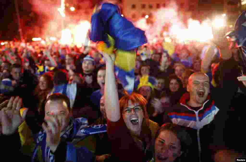 Para penggemar Bosnia dan Herzegovina merayakan gol melawan Argentina dalam pertandingan yang disiarkan langsung di alun-alun utama Sarajevo (16/5).&nbsp;(Reuters/Dado Ruvic)