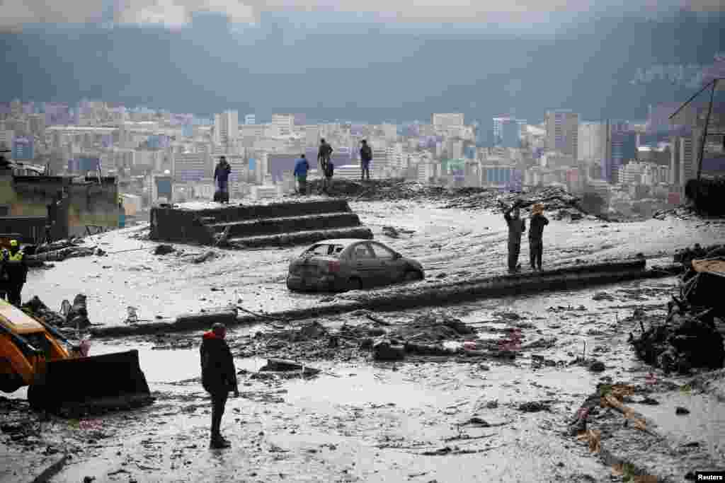 Residents are seen in an area of a landslide as firefighter rescue crews continue searching homes and streets covered by mud in Quito, Ecuador, Feb. 1, 2022.