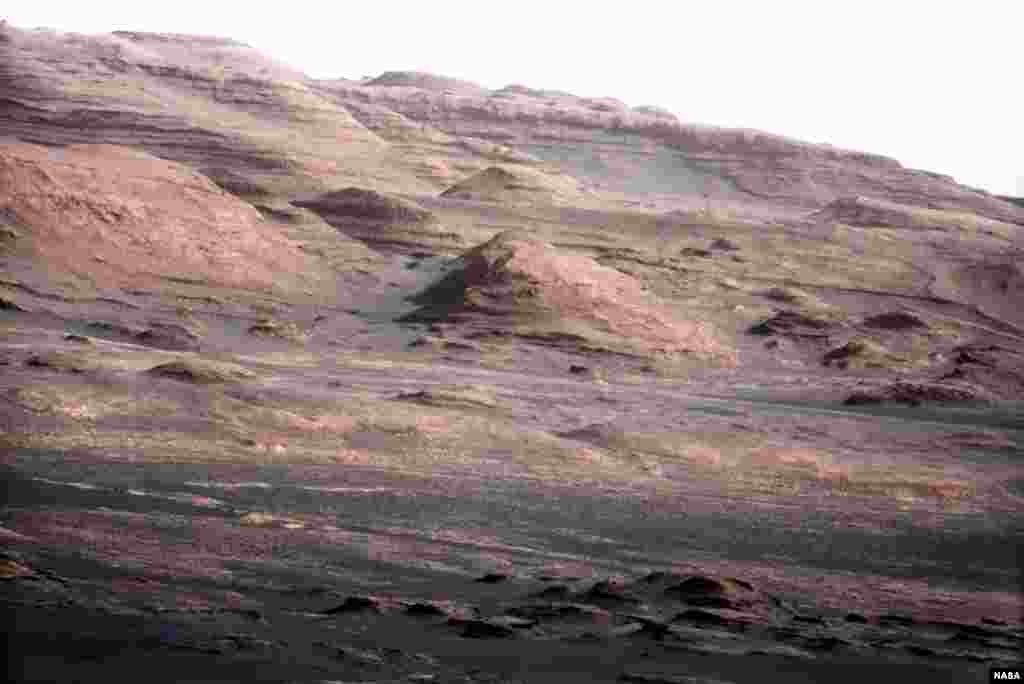 This image shows the base of Mount Sharp, the rover&#39;s eventual science destination. Scientists enhanced the color to show the Martian scene under the lighting conditions we have on Earth, which helps in analyzing the terrain. Основата н