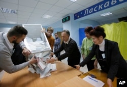Members of a local election commission open a ballot box to count votes after a day of election at a polling station in Kiev, Ukraine, Oct. 25, 2015.