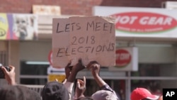 Vendors hold placards suggesting they will exercise their right to vote in the 2018 Presidential elections after they were removed from the streets of Harare, Wednesday, July, 8, 2015. Minor scuffles ensued as police officers drove out thousands of vendors selling their wares on the sidewalks and pavements of Harare. (AP Photo/Tsvangirayi Mukwazhi)