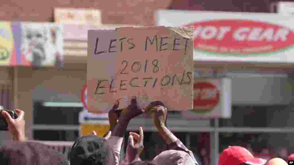 Vendors hold placards suggesting they will exercise their right to vote in the 2018 Presidential elections after they were removed from the streets of Harare, Wednesday, July, 8, 2015. Minor scuffles ensued as police officers drove out thousands of vendors selling their wares on the sidewalks and pavements of Harare. 