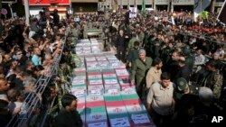 Flag-draped caskets of those who died in Saturday's terror attack on a military parade are laid out during a mass funeral, in the southwestern city of Ahvaz, Iran, Sept. 24, 2018. 