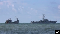 FILE - A Myanmar navy vessel tows a boat with migrants, off the country's Thameehla island, May 31, 2015.