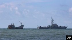 FILE - A Myanmar navy vessel tows a boat with migrants, off the country's Thameehla island, May 31, 2015.