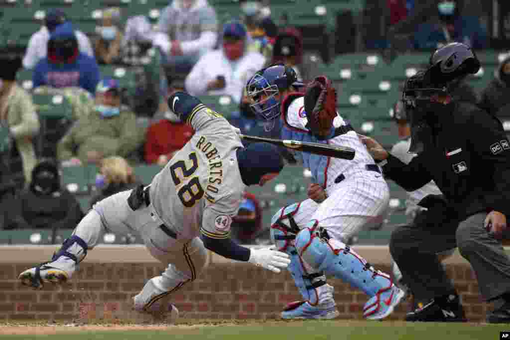 Milwaukee Brewers&#39; Daniel Robertson (28) is hit on the head by a pitch as Chicago Cubs catcher Willson Contreras reaches for the ball during the ninth inning of a baseball game in Chicago, Illinois, April 25, 2021.