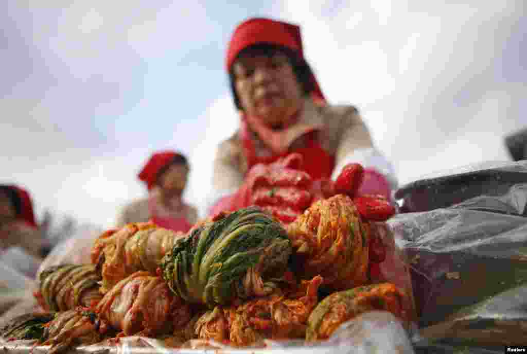 A woman makes traditional Korean side dish kimchi, or fermented cabbage, during the 2014 Seoul Kimchi Making and Sharing Festival at Seoul City Hall Plaza in Seoul, South Korea. More than 2,300 volunteers made 250 tons of kimchi to give away to needy people during the winter season.
