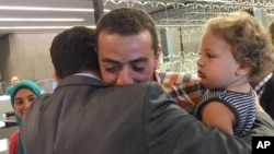 A colleague welcomes Egyptian Al-Jazeera English journalist Baher Mohammed, carrying son Haroon, upon his arrival in Doha, Qatar, Oct. 14, 2015. 