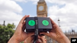 A man looks through a virtual reality device that shows a 360-degree view of the city of Aleppo, Syria, during an Amnesty International protest in Parliament Square, London, July 11, 2015.