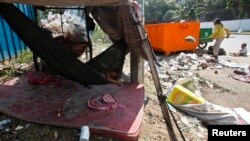 FILE PHOTO - A young girl sleeps in a hammock as her mother clears garbage, along a street in central Phnom Penh, Cambodia, October 3, 2014. REUTERS/Samrang Pring 