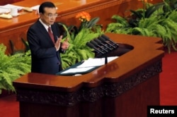 hina's Premier Li Keqiang claps as he stands at a podium during the opening session of the National People's Congress (NPC) at the Great Hall of the People in Beijing, March 5, 2016.