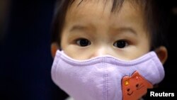 Seorang anak laki-laki mengenakan masker sebelum menerima vaksinasi Influenza di sebuah rumah sakit di Taipei, 9 November 2009.