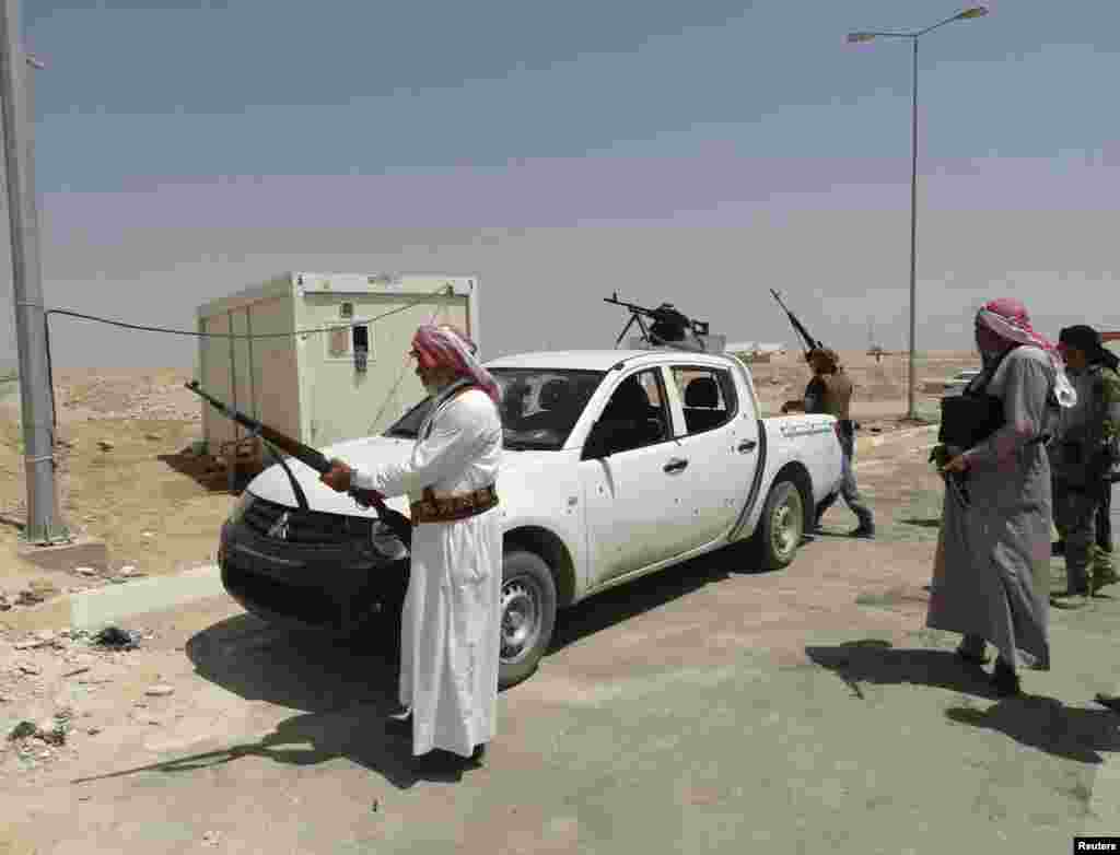 Tribal fighters carry their weapons during an intensive security deployment to fight militants of the Islamic State, in the town of Haditha, northwest of Baghdad, Aug. 25, 2014. 