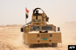 Iraqi government forces drive their armored vehicle, June 22, 2016, some 40 kilometers (25 miles) west of Qayyarah, during their operation to take the city and make it a launchpad for Mosul.