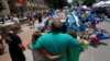 People hug at at a makeshift memorial at police headquarters following the multiple police shootings in Dallas, Texas, U.S., July 10, 2016.