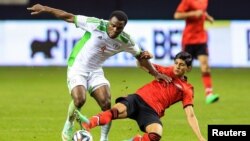 Tiền đạo đội tuyển quốc gia Mexico Alan Pulido (áo đỏ) tranh bóng với Emmanel Emenike của đội Nigeria (áo trắng) trong một trận đấu giao hữu.