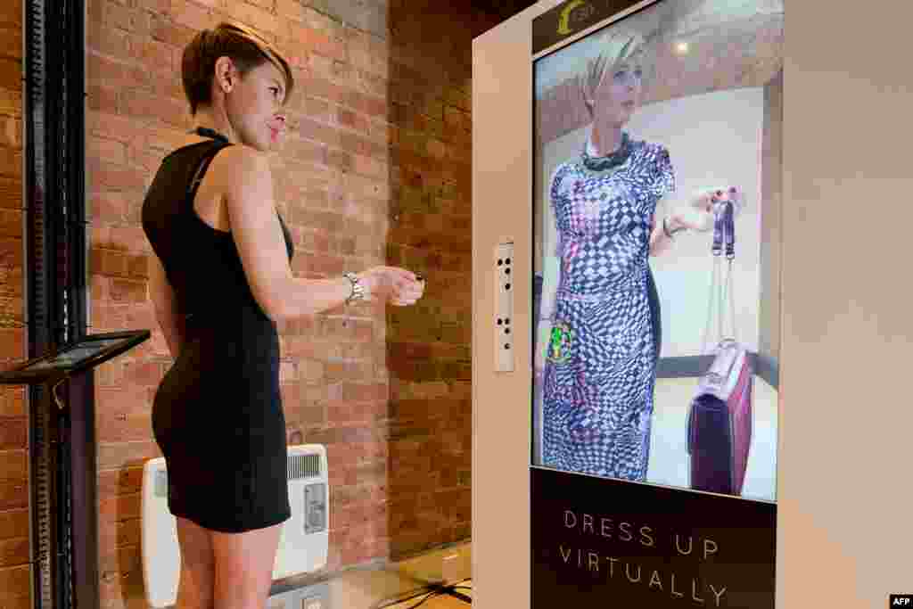 A woman tries out the Virtual Style Pod/Fashion 3D system at the FLux Innovation Lounge in east London. The technology uses body mapping software to superimpose items of clothing onto the customers body so that he or she can try on different styles without having to change clothes. The cameras track the customers movement, allowing them to see how the clothing moves and from all sides and angles.