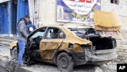 Ahmed Ali inspects his destroyed car after a car bomb explosion in Baghdad, Iraq, February 23, 2012.