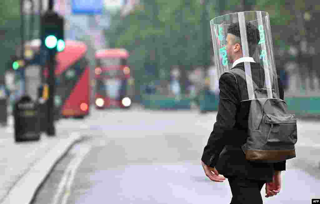 A pedestrian wearing a form of personal protective equipment as a measure to protect against COVID-19 walks across Oxford Street in central London, Britain.