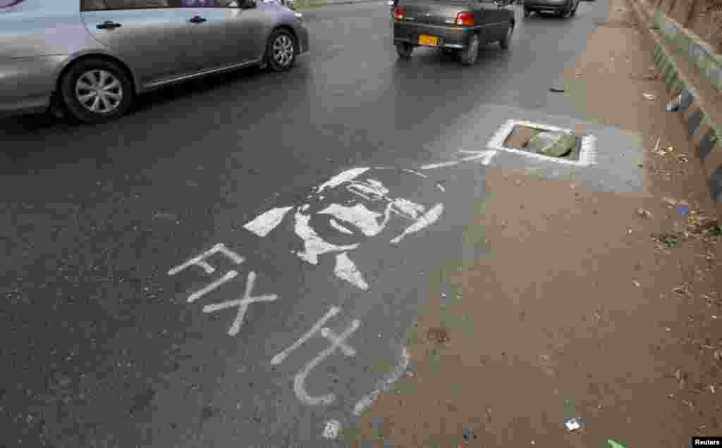  Vehicles move past a graffiti, depicting the provincial chief executive with the message "Fix It!", near an uncovered drain hole along a road in Karachi, Pakistan. According to local media, a group of activists launched an idea to promote a campaign-project to draw the attention of authorities towards civic issues by art, by spray painting stenciled images of lawmakers with messages.