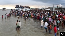 People gather on the banks of the River Padma after a passenger ferry capsized in Munshiganj district, Bangladesh, Aug. 4, 2014.
